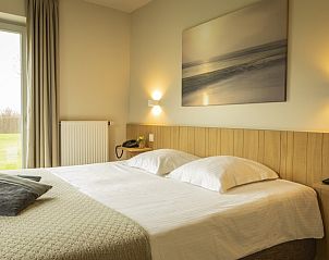 Comfortabele slaapkamer in Huyshoeve vakantiehuis in Knokke-Heist, met uitzicht op de groene omgeving van West-Vlaanderen.