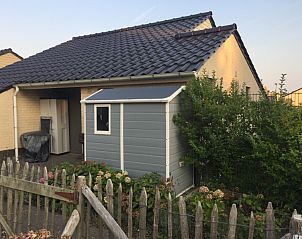 Achtertuin van Zee en Polder vakantiehuis, Westende, Belgische kust, met schuur en bloemen.