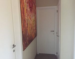 Kunstzinnige hal in Zee en Polder vakantiehuis, Westende, Belgische kust, met kleurrijk schilderij.