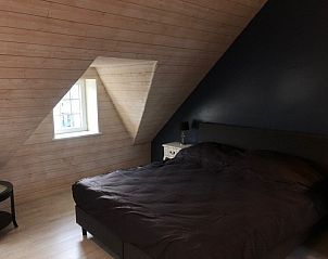 Zolderkamer in Vakantiehuisje aan de IJzer, Diksmuide, met houten wand en dakraam.