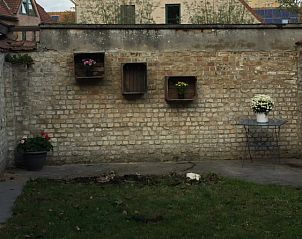 Tuin van Vakantiehuisje aan de IJzer, Diksmuide, met bakstenen muur en bloembakken.