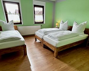 Sfeervolle slaapkamer in Vakantiehuisje in Alheim, Hessen met houten vloeren en groene muren, perfect voor een ontspannen verblijf.