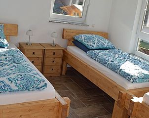 Gezellige slaapkamer in Erlebnishtte Unzenberg, vakantiehuis in Eifel/Moezel/Hunsrck, Duitsland, met houten bedden en frisse inrichting.
