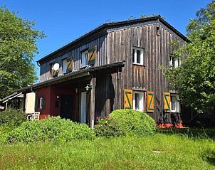 Vacation home in Mrlenbach with rustic wooden facade surrounded by green nature in Eifel, Moselle, Hunsrck, Germany.