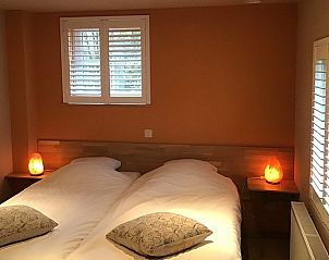 Sfeervolle slaapkamer met oranje accenten in Gastenverblijf Wisteria, Herne.