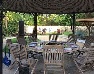 Overdekt terras met ronde tafel in Gastenverblijf Wisteria, Herne.
