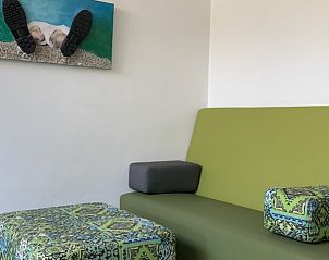Modern living room of vacation home Castor in Oosterend, Terschelling, with colorful sofa and art on the wall.