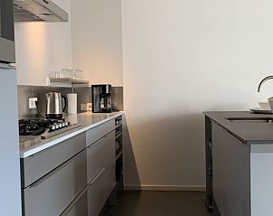 Sleek kitchen in vacation home Castor in Oosterend, Terschelling, with modern appliances and wooden ceiling.