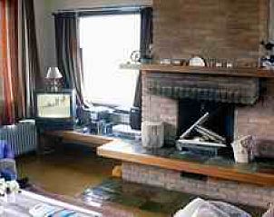 Cozy living room with fireplace in Bungalow De Wielewaal, West aan Zee, Terschelling, perfect for relaxing evenings on the Wadden Islands.