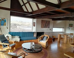 Cozy living room of The Helmhoeve vacation home in Midsland aan Zee, Terschelling with wooden furnishings.