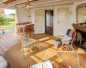 Ruime eetkamer in Vlakke Strand vakantiehuis, Midsland aan Zee, Terschelling met houten vloer en toegang tot het terras.