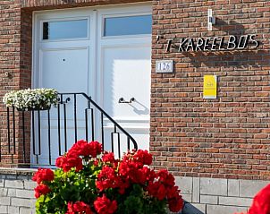 Ingang van 't Kareelbos vakantiehuis in Wezemaal, Vlaams-Brabant, met kleurrijke bloemen en uitnodigende sfeer.