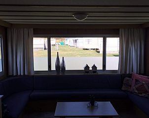 Helles Wohnzimmer im Mobilheim Kanoet, West Terschelling, mit Blick auf die grne Umgebung.