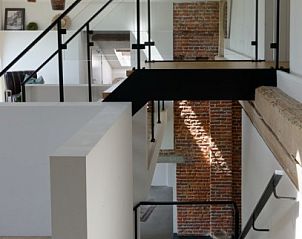 Elegante trap in De Woestijn - Vakantiewoning De Schuur, Roosdaal, Vlaams-Brabant met glazen balustrade en bakstenen muur.