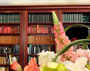 Gezellige leeshoek in Bastion Hotel Utrecht, Utrecht, met bloemen en boeken voor ontspanning.