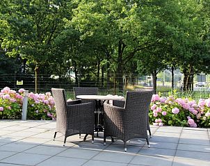 Buitenterras van Bastion Hotel Utrecht, Utrecht, met comfortabele stoelen en bloeiende hortensia's.