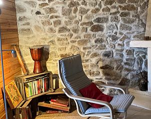 Gezellige leeshoek in Huisje in Saint Gervais d'Auvergne, vakantiehuis in Auvergne, Frankrijk met stenen muur en comfortabele stoel.