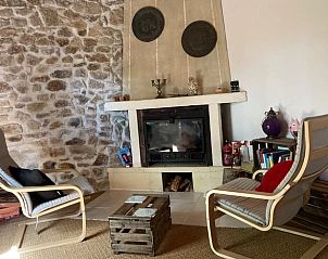 Gezellige woonkamer in Huisje in Saint Gervais d'Auvergne, Frankrijk, met stenen muur en open haard.