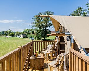Ontspan op de veranda van Papillon, een glamping lodge in Saint Dsir, Auvergne, met uitzicht op groene velden.
