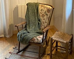 Cozy sitting area in Cottage in Saint-Prix, Burgundy, with rustic chair and wooden stool.