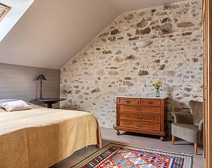 Gemtliches Schlafzimmer im Ferienhaus in Millay, Burgund, mit Steinmauer und Holzmbeln fr eine authentische franzsische Atmosphre.