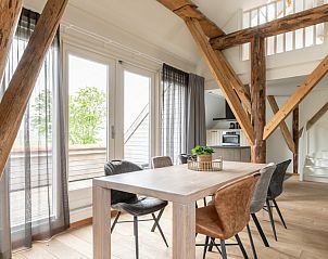 Lichte eetruimte in Hooivak vakantiehuis, Hollum, Ameland met uitzicht op terras en groene omgeving.