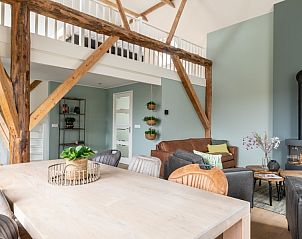 Ruime woonkamer in Hooivak appartement, Hollum, Ameland met gezellige zithoek en open haard.