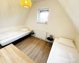 Slaapkamer met twee eenpersoonsbedden in De Miede, Nes, Ameland, ideaal voor een ontspannen verblijf op de Waddeneilanden.