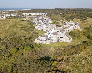 Luchtfoto van Zand appartement in Nes, Ameland, omgeven door groene duinen en natuur.