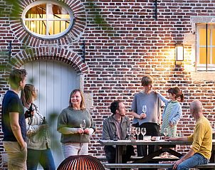 Gemtliche Gruppe von Menschen, die ein Getrnk auf der Terrasse des Ferienhauses in Tongerlo, Antwerpen, Belgien, genieen.