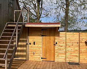 Holzterrasse mit Treppe im Ferienhaus in Minderhout, Antwerpen, Belgien, umgeben von Natur und rustikalem Charme.