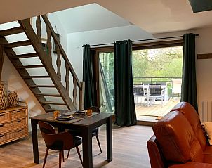 Gemtliches Wohnzimmer im Ferienhaus in Noyal-Muzillac, Bretagne mit Blick auf die Terrasse und die grne Umgebung.