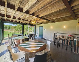 Gezellige binnenruimte van vakantiehuis Lactea in Schilde, Antwerpen met houten plafond en uitzicht op de groene omgeving.