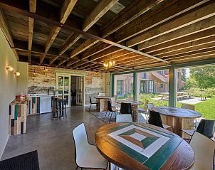 Binnenruimte van vakantiehuis Lactea in Schilde, Antwerpen met rustieke houten balken en uitzicht op groene tuin.