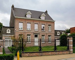 Vooraanzicht van Amand'eau vakantiehuis in Sint-Amands, Antwerpen met klassieke bakstenen gevel en groene tuin.