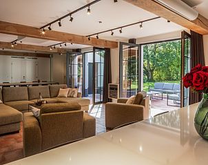 Stijlvolle woonkamer van Mushoeve in Zoersel, Antwerpen met grote ramen en uitzicht op de tuin.