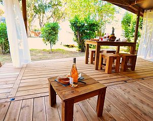 Genieen Sie die Ruhe auf der Veranda der Tent Lodge Riada, einer Glamping-Lodge in Moriani-Plage auf Korsika, umgeben von ppiger Natur.