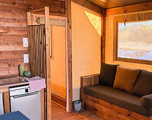 Gezellige binnenruimte van de Cotton Flower Canvas Lodge Comfort in Treignac, Limousin, met houten interieur en comfortabele bank.