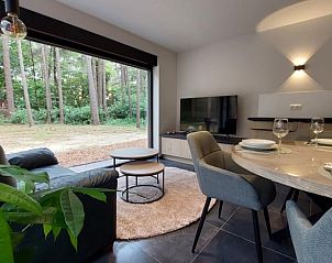 Gezellige woonkamer in Vakantiehuis in Lille, Antwerpen, Belgi met uitzicht op bosrijke natuur door grote ramen.