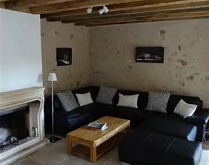 Gezellige woonkamer in vakantiehuis Le Marronnier, Lignac, Centre, Frankrijk met comfortabele zithoek en rustieke stenen muren.