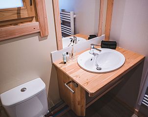 Stilvolles Badezimmer im Montana Chalet Vista, Ferienhaus in Ubaye-Serre-Ponon, Provence, mit Holzwaschbecken und modernen Annehmlichkeiten.