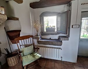 Gemtliche Einrichtung eines Ferienhauses in Le Bez, Frankreich, mit rustikalen Details und einem einladenden Sessel am Fenster.