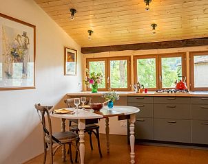 Gemtliche Kche im Ferienhaus in Castelnau-Durban, Frankreich, mit Holzdecke und Blick auf die grne Umgebung.