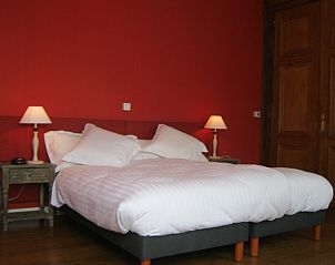 Chateau de Moulin le Comte in Aire-sur-la-Lys biedt een elegante slaapkamer met warme rode muren voor een comfortabel verblijf in Nord / Pas de Calais.
