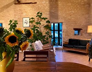 Gezellige woonkamer van Huisje in Veyrignac, Aquitaine, met rustieke stenen muren en zonnebloemen, perfect voor een vakantiehuis in Frankrijk.