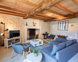 Gezellige woonkamer van Les Ecures 1 vakantiehuis in Champagne-et-Fontaine, Aquitaine, met rustieke houten balken en moderne inrichting.