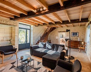 Gezellige woonkamer in Les Escures 2, een vakantiehuis in Champagne-et-Fontaine, Aquitaine, met rustieke houten balken en stenen muren.