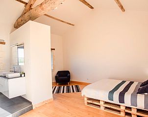 Stijlvolle slaapkamer in Les Escures 2 vakantiehuis, Champagne-et-Fontaine, Aquitaine met houten balken en modern comfort.