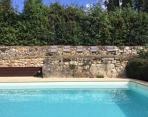 Relax by the pool of vacation home la Fageole in Domme, Aquitaine, surrounded by green nature and rustic stone walls.