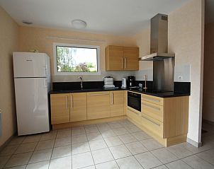 Modern kitchen in vacation home La Roseraie, Terrasson-Lavilledieu, Aquitaine, France with wooden cabinets and spacious refrigerator.